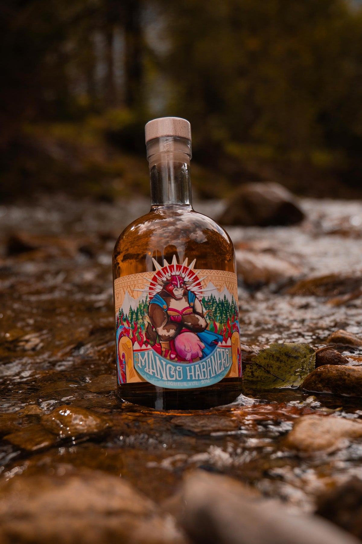 MaHa Shot mango habanero liqueur bottle standing on stones in a mountain stream